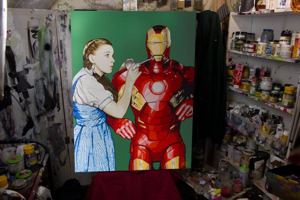 Pop art mashup painting of Iron Man replacing the Tin Man in the Wizard of Oz, with Dorothy giving him oil, titled "We're Not in New York Anymore."