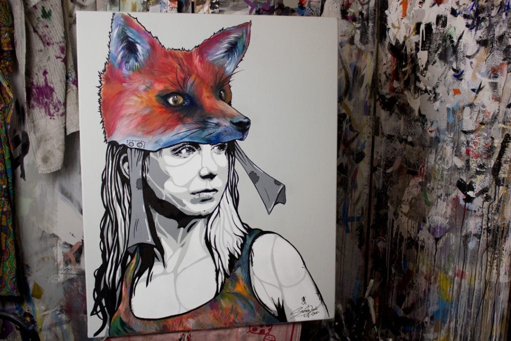 painting with a woman who has a fox as a hat painting in a art studio